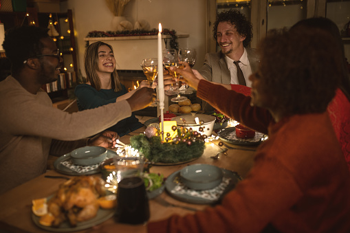 Photo of cheerful friends toasting on Christmas dinner at home